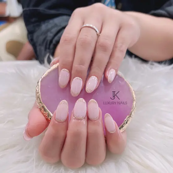 Soft nude almond nails resting on a pink K&J Luxury Nails coaster